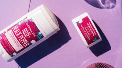 Schmidt's Rose+Black Pepper Hemp Seed Oil Deodorant with cap off on a purple table